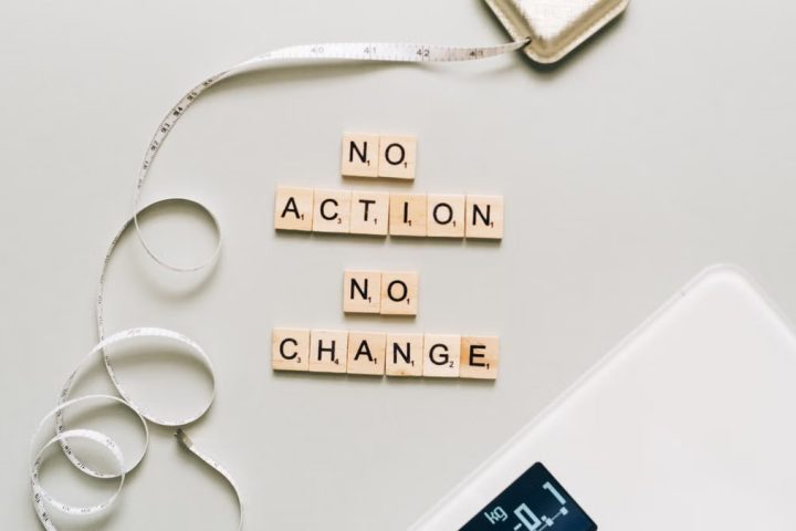 Motivational concept with scrabble tiles spelling no action no change alongside a measuring tape and scale.